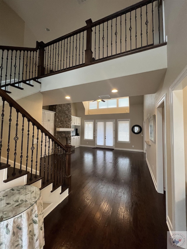 interior space featuring a towering ceiling, ceiling fan, and dark hardwood / wood-style floors