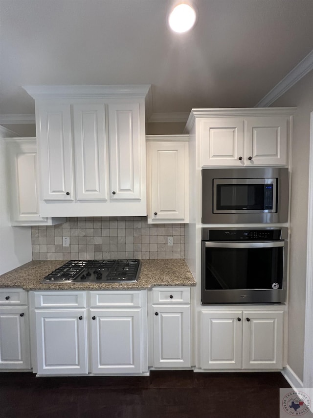 kitchen with backsplash, white cabinetry, ornamental molding, and stainless steel appliances