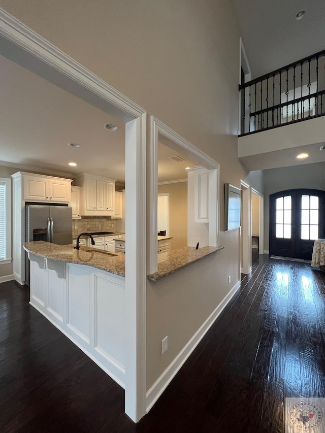 kitchen featuring stainless steel fridge with ice dispenser, white cabinetry, french doors, ornamental molding, and kitchen peninsula