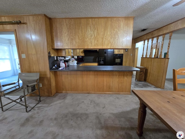 123 Texas Ln, New Boston, TX 75570 - kitchen featuring black appliances, a textured ceiling, wooden walls, dark countertops, and a peninsula