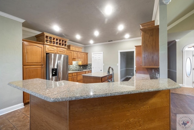 kitchen featuring light tile patterned flooring, kitchen peninsula, tasteful backsplash, and stainless steel fridge