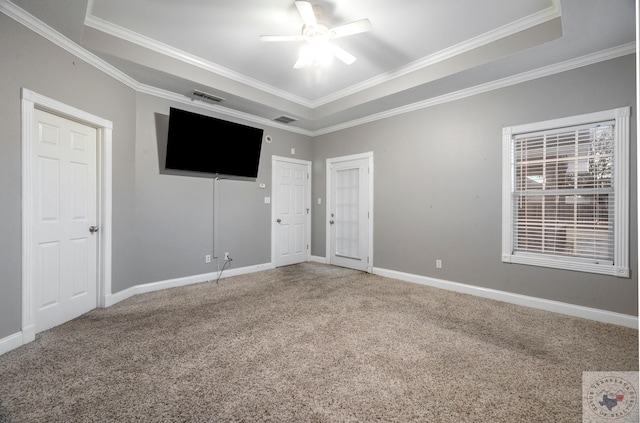 unfurnished bedroom featuring ceiling fan, carpet flooring, crown molding, and a tray ceiling