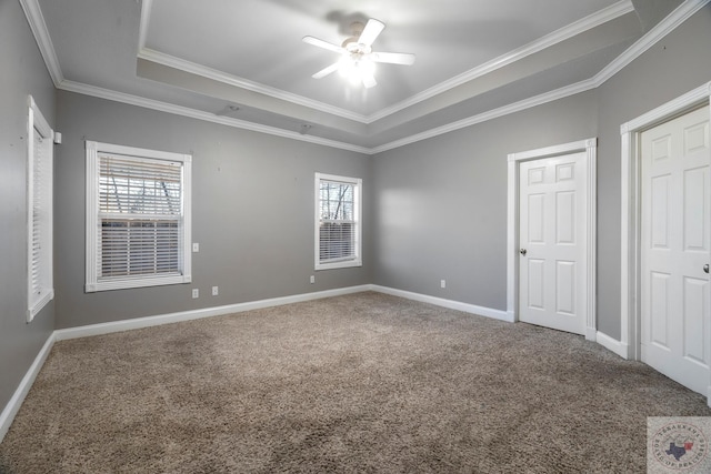 unfurnished bedroom featuring crown molding, multiple windows, a tray ceiling, and ceiling fan