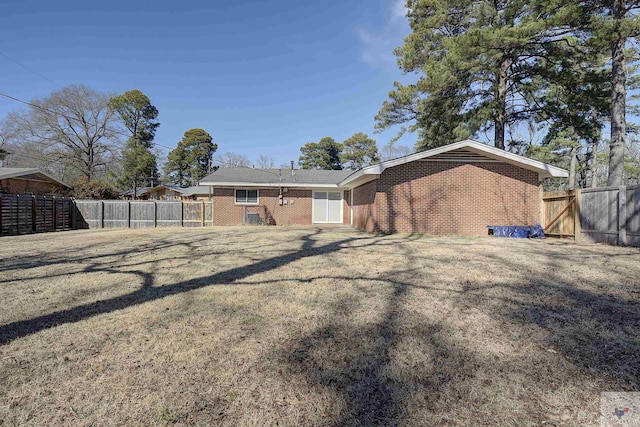 back of property with a yard, fence, and brick siding