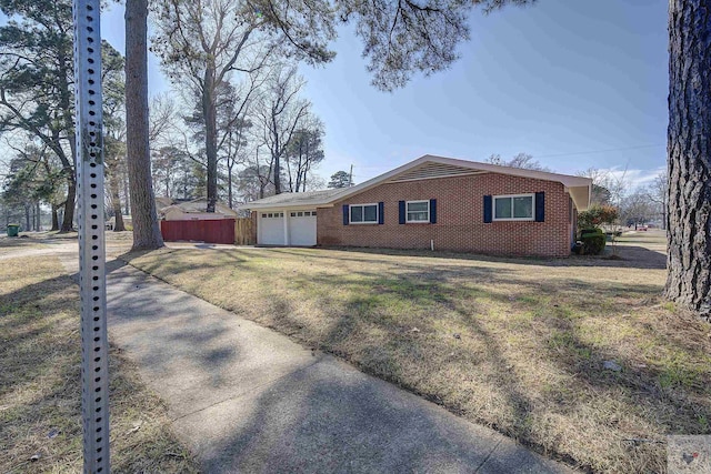 view of side of property featuring a garage, a yard, brick siding, and fence