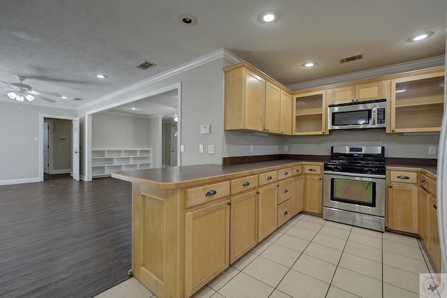 kitchen with dark countertops, visible vents, appliances with stainless steel finishes, and light brown cabinetry