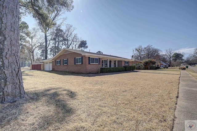 view of property exterior with a garage, a lawn, and brick siding