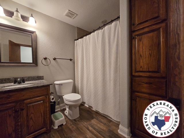 7 Summer Ln, Texarkana, TX 75503 - full bath featuring wood finished floors, toilet, vanity, and a shower with curtain