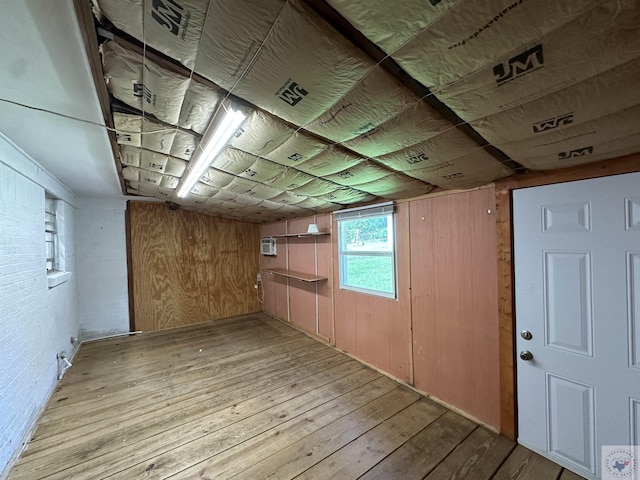 basement with wood walls, light hardwood / wood-style flooring, and a wall unit AC