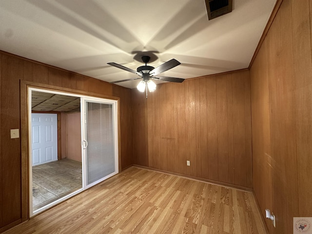 unfurnished bedroom with wood walls, light hardwood / wood-style flooring, and ceiling fan