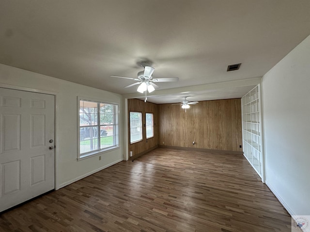 interior space featuring wood walls, ceiling fan, and dark hardwood / wood-style flooring