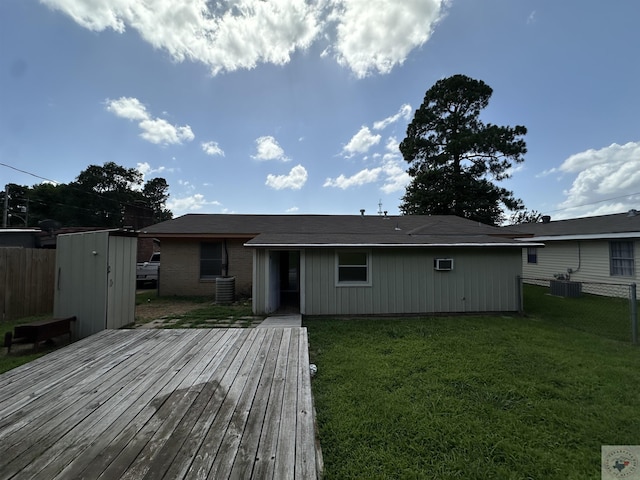 rear view of house featuring central AC unit, a wooden deck, a yard, and a storage shed