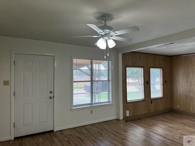 entryway featuring hardwood / wood-style floors, wooden walls, and ceiling fan