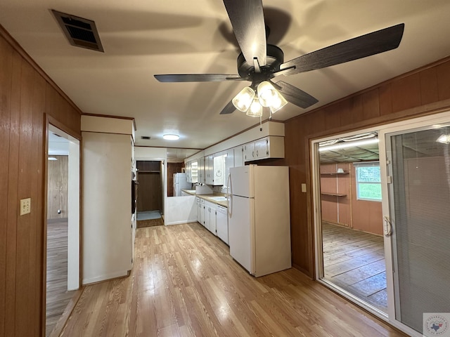 kitchen featuring white cabinets, white refrigerator, wood walls, and light wood-type flooring