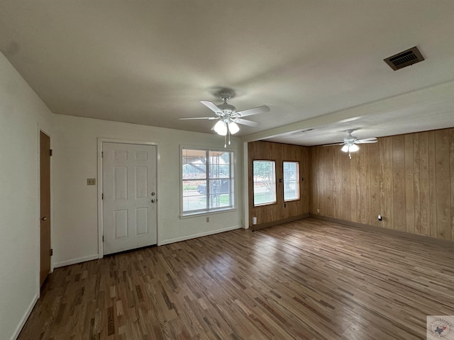 interior space featuring hardwood / wood-style flooring, wood walls, and ceiling fan