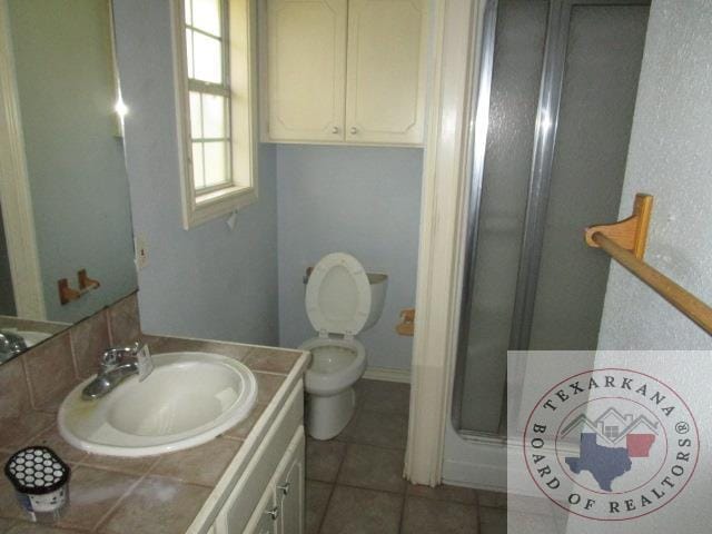 bathroom featuring tile patterned floors, walk in shower, vanity, and toilet