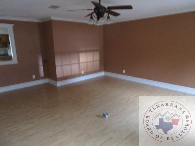 spare room featuring light wood-type flooring, ceiling fan, and ornamental molding