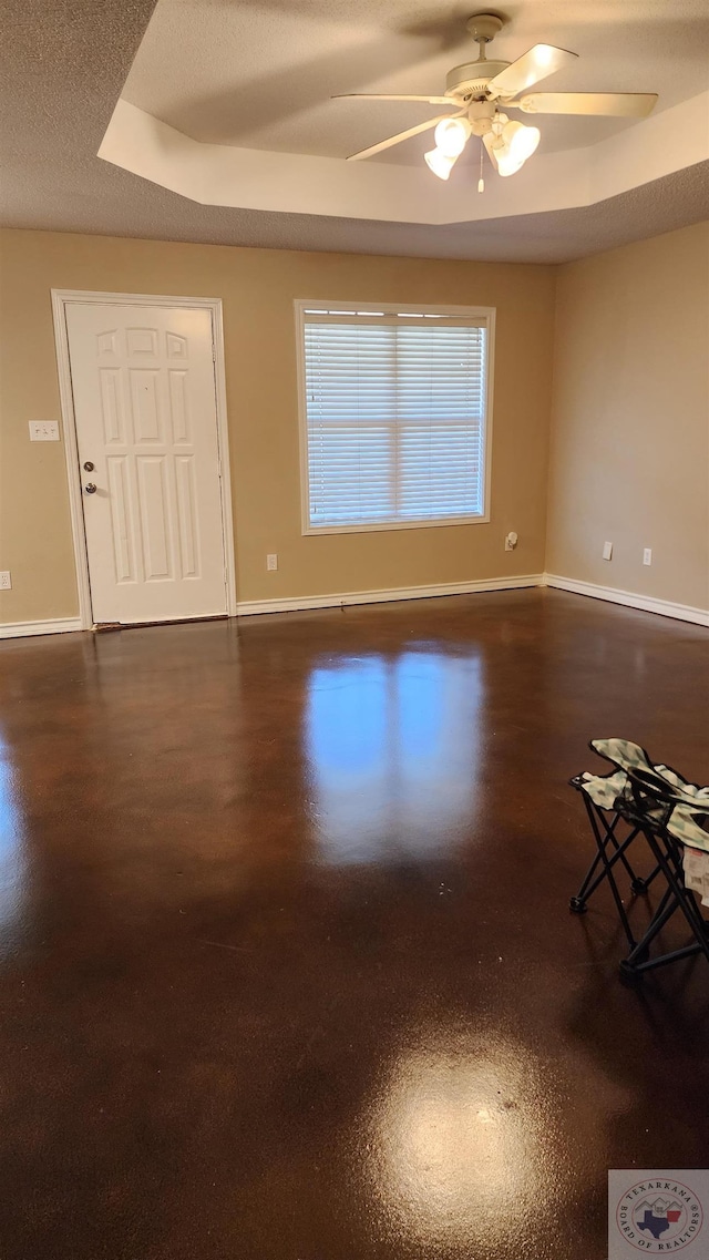 unfurnished room featuring ceiling fan, a textured ceiling, and a raised ceiling