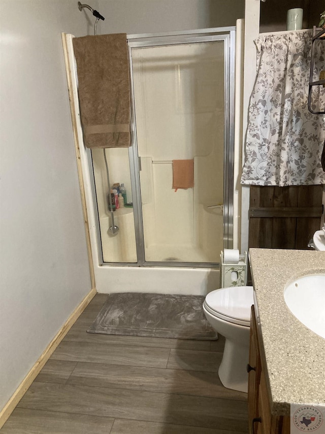 bathroom with vanity, toilet, an enclosed shower, and wood-type flooring