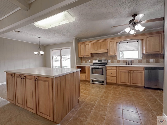 kitchen featuring appliances with stainless steel finishes, sink, a kitchen island, pendant lighting, and ceiling fan with notable chandelier