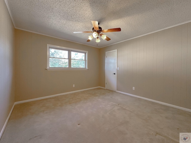 carpeted spare room with ceiling fan, a textured ceiling, and ornamental molding