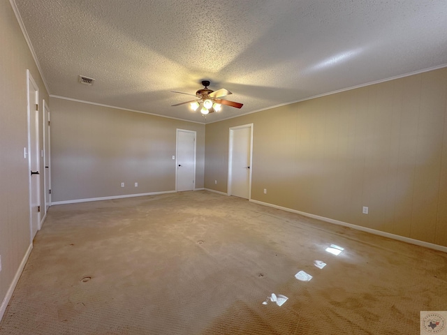 carpeted empty room featuring ceiling fan, crown molding, and a textured ceiling