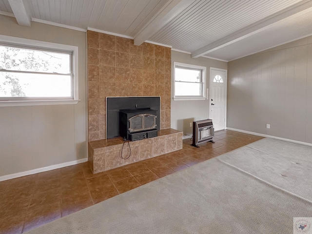 unfurnished living room featuring a wood stove, heating unit, beamed ceiling, and tile patterned flooring