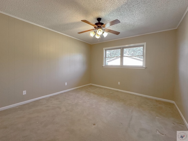 carpeted empty room with ceiling fan, crown molding, a textured ceiling, and wooden walls