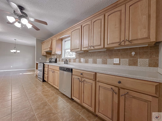 kitchen with pendant lighting, sink, light tile patterned flooring, ceiling fan with notable chandelier, and stainless steel appliances