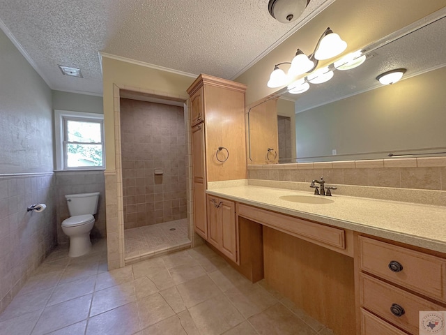 bathroom featuring toilet, tile walls, a tile shower, ornamental molding, and vanity