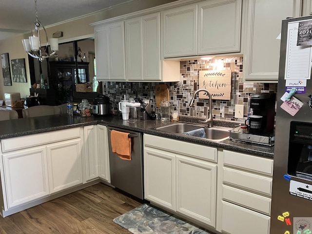 kitchen with appliances with stainless steel finishes, a chandelier, decorative backsplash, sink, and light wood-type flooring