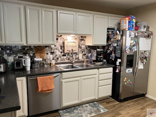 kitchen with light hardwood / wood-style floors, appliances with stainless steel finishes, white cabinetry, sink, and backsplash