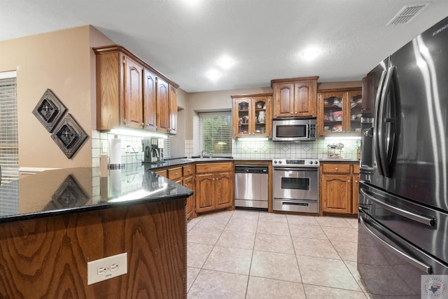 kitchen with stainless steel appliances, tasteful backsplash, sink, kitchen peninsula, and light tile patterned floors