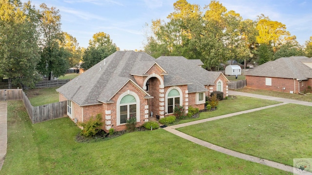 english style home featuring a front yard and a storage shed