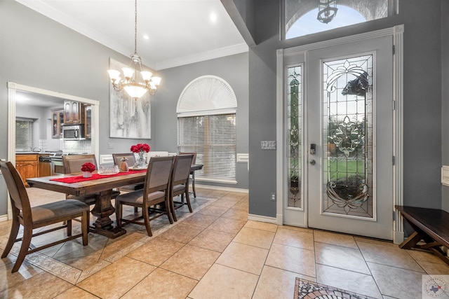 tiled foyer entrance with crown molding and a chandelier