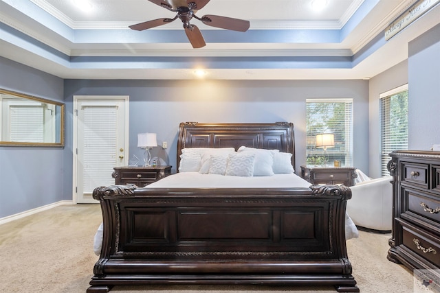 carpeted bedroom with crown molding, a tray ceiling, and ceiling fan