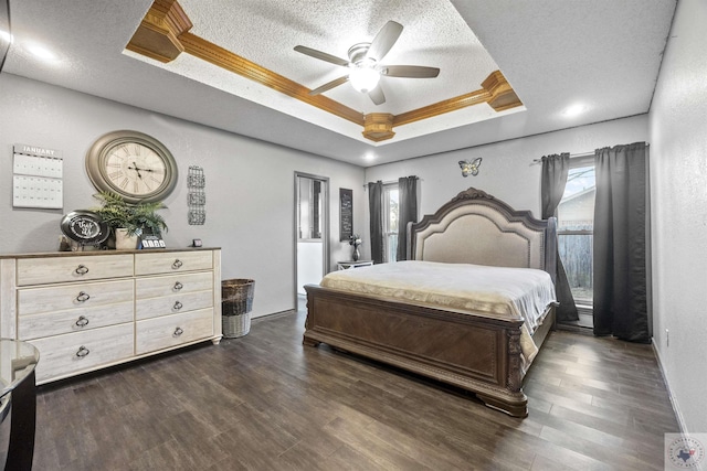 bedroom featuring dark hardwood / wood-style flooring, a tray ceiling, a textured ceiling, and ceiling fan