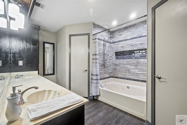 bathroom featuring hardwood / wood-style flooring, vanity, shower / tub combo, and a textured ceiling