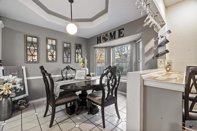 tiled dining area featuring crown molding and a raised ceiling