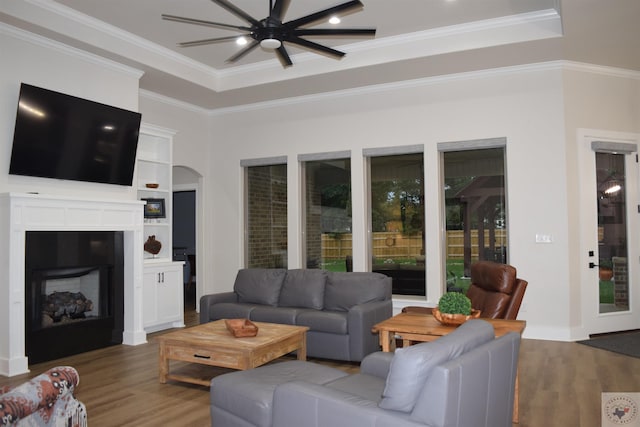 living room with hardwood / wood-style flooring, a raised ceiling, ornamental molding, and ceiling fan