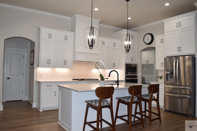 kitchen with decorative light fixtures, white cabinets, a kitchen island with sink, and appliances with stainless steel finishes