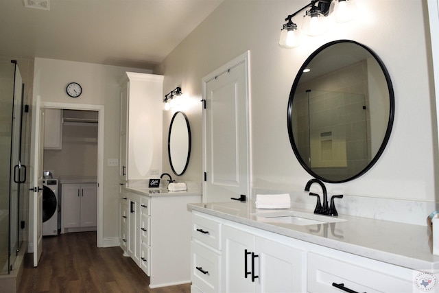 bathroom featuring hardwood / wood-style flooring, vanity, washer / dryer, and a shower with door