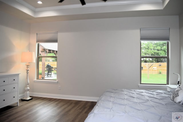 bedroom with a tray ceiling, dark hardwood / wood-style floors, and crown molding