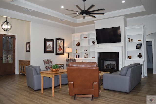 living room featuring ornamental molding, hardwood / wood-style flooring, ceiling fan with notable chandelier, and a raised ceiling