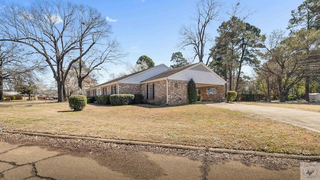 view of front of home with brick siding, a front yard, and driveway