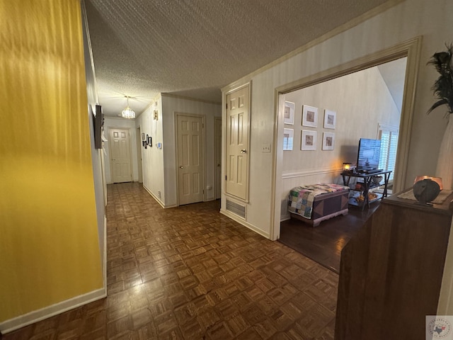 corridor with a textured ceiling and dark parquet flooring