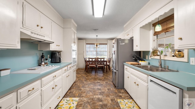 kitchen featuring under cabinet range hood, stone finish flooring, a sink, white appliances, and white cabinets