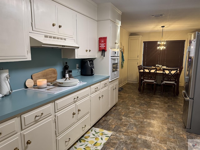 kitchen with white appliances, pendant lighting, white cabinets, and a notable chandelier