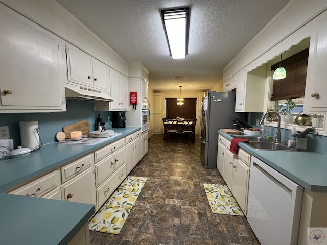 kitchen featuring sink, white appliances, white cabinets, and hanging light fixtures