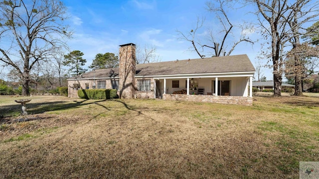 rear view of property with a patio area, a lawn, and a chimney